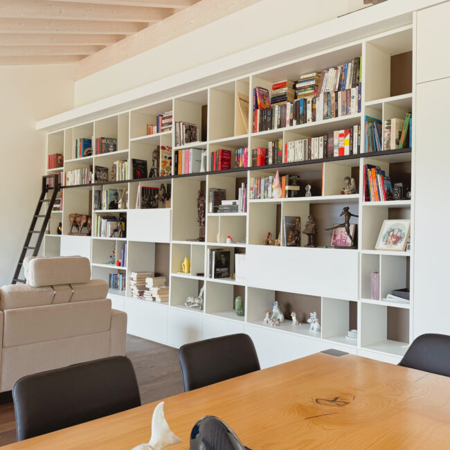 Libreria su misura a tutta parete con scaletta e contenitori integrati
