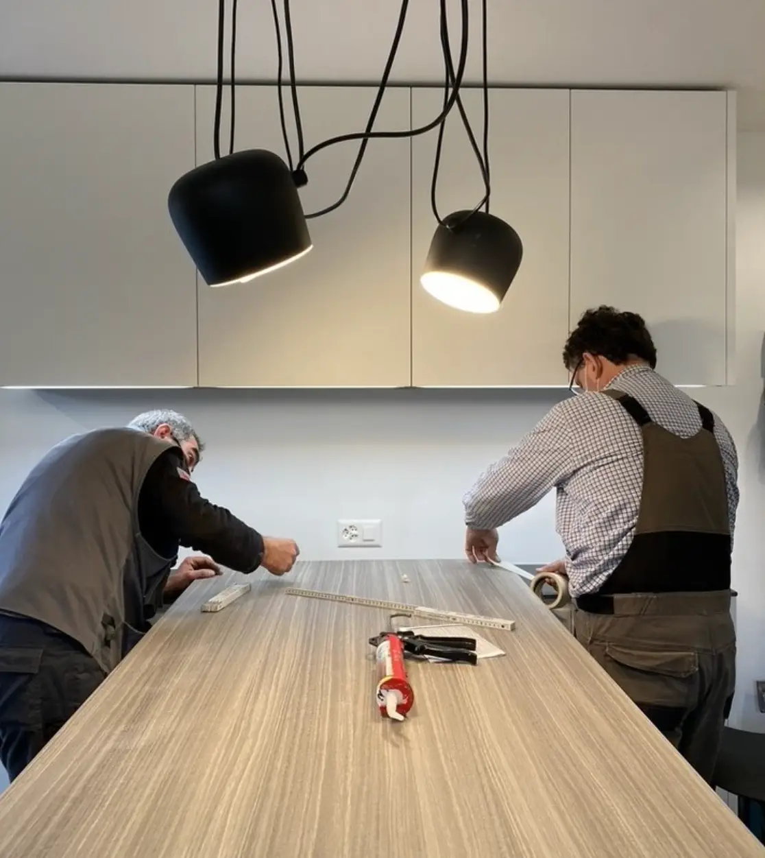Due montatori lavorano alla finitura del piano di una cucina